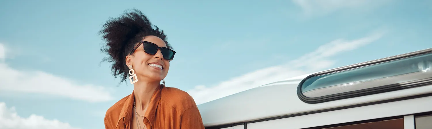 A smiling woman in sunglasses under a bright sky